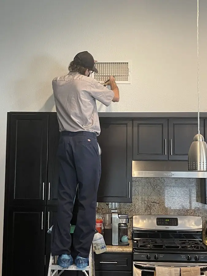 Technician inspecting an air vent during HVAC service in Maywood
